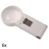 White, round lens hand held magnifier with grey on/off switch on rectangular handle labeled 6x.